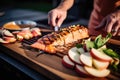 person garnishing bbq salmon with apple slices
