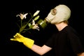 Person in a gas mask smells a flower Royalty Free Stock Photo