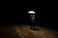 A person gaze at the light from a white umbrella in the dark