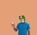 Person gesture with frog mask catching a professional baseball in hand as amateur on orange background Royalty Free Stock Photo