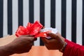 Person giving a cash gift in an envelope wrapped with a ribbon.