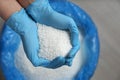 Person in gloves holding pile of ammonium nitrate pellets over bag, top view. Mineral fertilizer