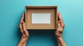 A person is grasping a cardboard box that has an empty white label attached to it, set against a blue background Royalty Free Stock Photo
