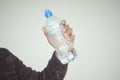A person is grasping a plastic bottle with their fingers and thumb