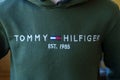 Person in Green Tommy Hilfiger Sweatshirt close up logo. Selective focus
