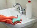 Person hand holding a mint sponge for cleaning bathroom sink and faucet Royalty Free Stock Photo