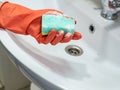 Person hand holding a mint sponge for cleaning bathroom sink and faucet Royalty Free Stock Photo