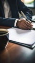 person hand holding a pen, signing a contract on desk with a laptop and coffee cup in the background Royalty Free Stock Photo