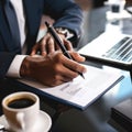 person hand holding a pen, signing a contract on desk with a laptop and coffee cup in the background Royalty Free Stock Photo