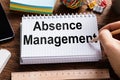 Person Writing Absence Management Word In Notebook With Pencil