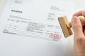 Person hand holding rubber stamp over paid invoice