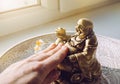 Person hand rubbing small golden laughing Buddha figurine tummy. It believed to bring happiness, good fortune and wealth.