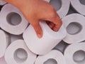 A person hand taking a toilet roll from heap of toilet paper rolls Royalty Free Stock Photo