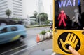 Person hand touch push button of pedestrian crosswalk signal sign located at a busy city street