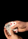 Person hands are holding playing cards three sixes close up on black background