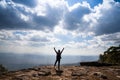 A person hands up standing on rocky mountain looking out at scenic natural Royalty Free Stock Photo
