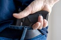 Hided handgun under the denim belt. A person is hiding a handgun under the denim belt. Royalty Free Stock Photo