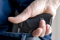 A person is hiding a handgun under the denim belt. Royalty Free Stock Photo