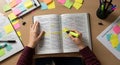 Person Highlighting Text in Open Book While Studying at Desk Royalty Free Stock Photo