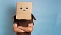 A person with his head stuck in a cardboard box with an expressionless grimace. A man hiding his head in a cardboard box.