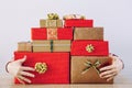 Person hoarding red cold color boxes Christmas presents. Guarding hands showing behind big gift pile.