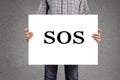 Person holding banner with SOS message. Royalty Free Stock Photo