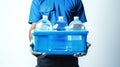 Person holding a blue crate filled with water bottles. Light background. Concept of water delivery, hydration service Royalty Free Stock Photo