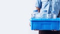 Person holding a blue crate filled with water bottles. White background. Banner. Copy space. Concept of water delivery Royalty Free Stock Photo