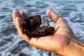 Person holding broken glass in hand on the beach. Warning, Be careful with your feet. Danger of broken glass in the sea sand.