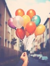 Person holding a bunch of colorful balloons in front of a street