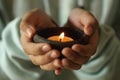 Person holding a candle. Junior girl holding candle light in a traditional ceramic bowl in hands. Royalty Free Stock Photo