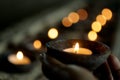 Person holding candle light in the dark on candles bokeh lights background. Love hope and peace concept