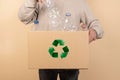 Person holding a cardboard box with plastic bottles and a recycling sign on it Royalty Free Stock Photo