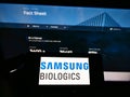 Person holding cellphone with business logo of biotechnology company Samsung Biologics Co Ltd on screen in front of website. Royalty Free Stock Photo