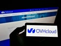 Person holding cellphone with business logo of French cloud computing company OVH Groupe SAS on screen in front of web page.