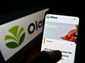 Person holding cellphone with logo of agribusiness company Olam International Limited on screen in front of website.