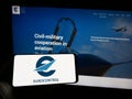 Person holding cellphone with logo of air traffic management organization Eurocontrol on screen in front of webpage.