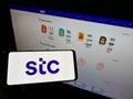 Person holding cellphone with logo of Arabian carrier Saudi Telecom Company (STC) on screen in front of company website.