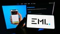 Person holding cellphone with logo of Australian financial company EML Payments Ltd on screen in front of business website.
