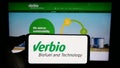 Person holding cellphone with logo of biofuel company Verbio Vereinigte Bioenergie AG on screen in front of webpage. Royalty Free Stock Photo