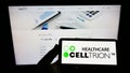 Person holding cellphone with logo of biopharmaceutical company Celltrion Inc. on screen in front of business webpage.