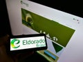 Person holding cellphone with logo of Brazilian pulp manufacturer Eldorado Brasil Celulose on screen in front of website.