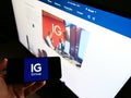 Person holding cellphone with logo of British financial services company IG Group Holdings Plc. on screen with website.