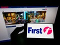 Person holding cellphone with logo of British transport company FirstGroup plc on screen in front of business website.