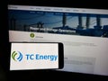 Person holding cellphone with logo of Canadian company TC Energy Corporation on screen in front of business webpage.