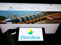 Person holding cellphone with logo of Centrais ElÃÂ©tricas Brasileiras SA (Eletrobras) on screen in front of website. Royalty Free Stock Photo