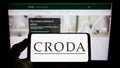 Person holding cellphone with logo of chamicals company Croda International plc on screen in front of business webpage. Royalty Free Stock Photo
