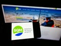 Person holding cellphone with logo of Chilean company Sociedad Quimica y Minera de Chile (SQM) on screen with website.