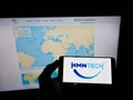 Person holding cellphone with logo of Chinese submarine network company HMN Tech on screen in front of business webpage.