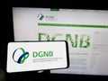 Person holding cellphone with logo of Deutsche Gesellschaft fÃ¼r Nachhaltiges Bauen (DGNB) on screen with web page.